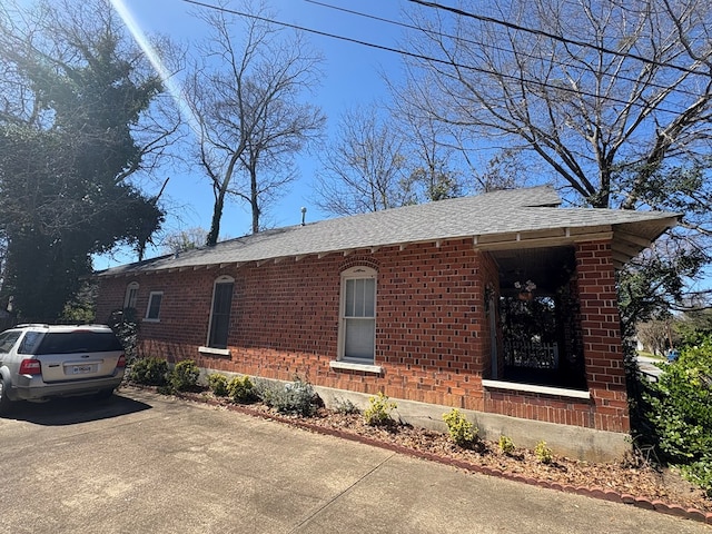 view of side of property with brick siding and a shingled roof