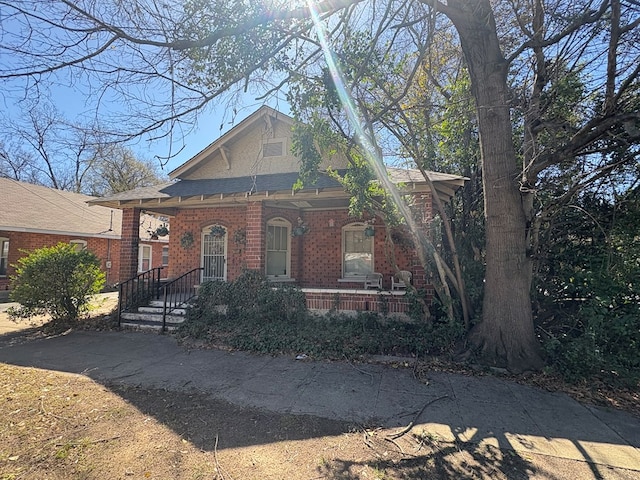 view of front of home with a porch, brick siding, and a shingled roof