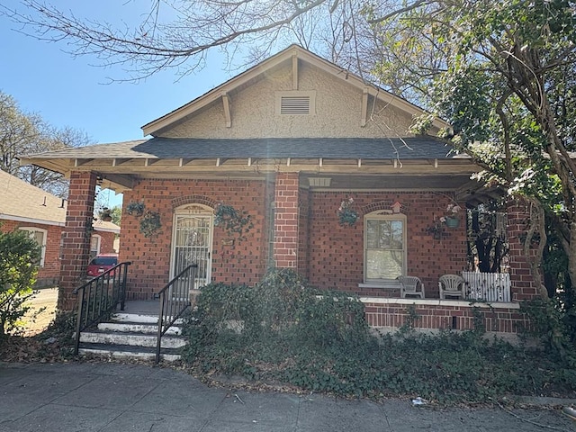 bungalow-style home with brick siding, roof with shingles, and covered porch