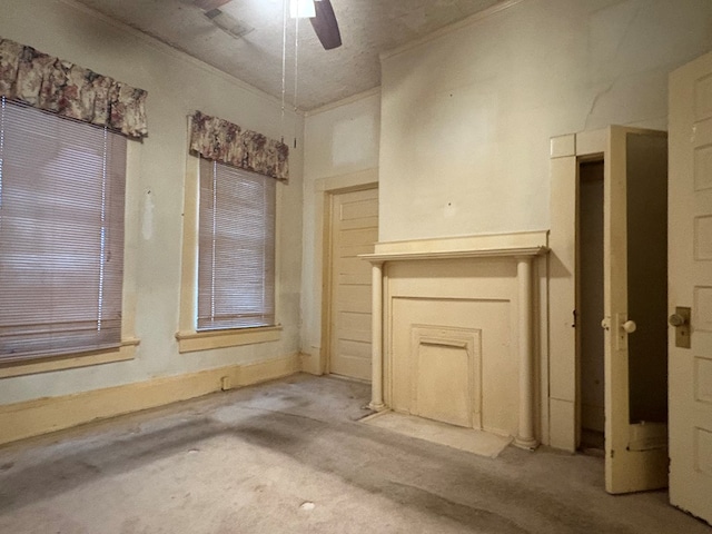 unfurnished living room with a ceiling fan, carpet flooring, and ornamental molding