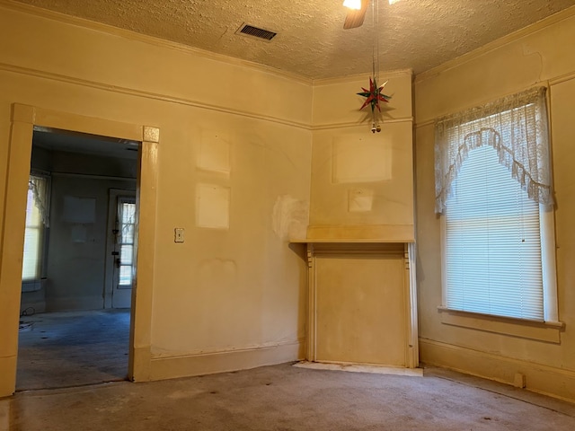 empty room featuring a textured ceiling, visible vents, ceiling fan, and carpet
