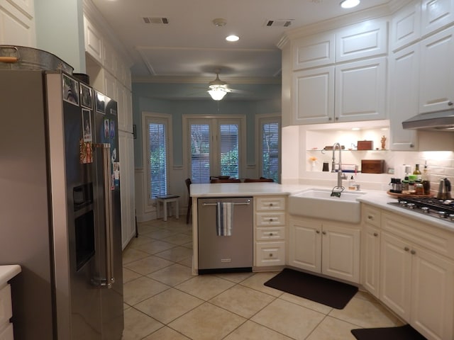 kitchen with a peninsula, appliances with stainless steel finishes, light countertops, and white cabinetry