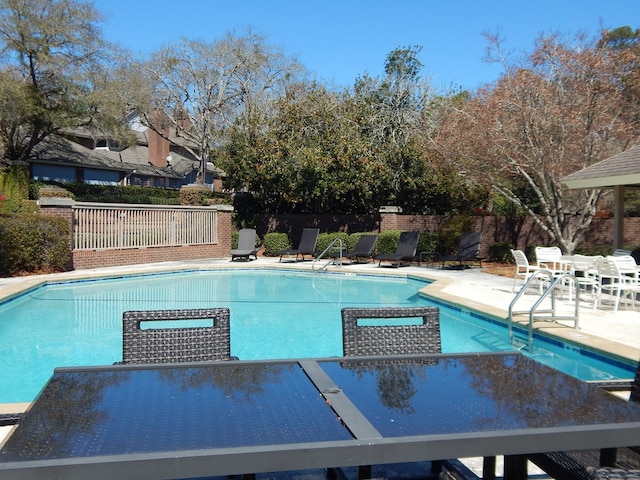 community pool with outdoor dining area, a patio area, and fence