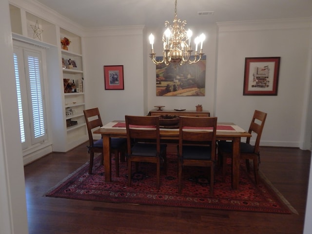 dining area with crown molding, visible vents, built in features, dark wood-style floors, and an inviting chandelier