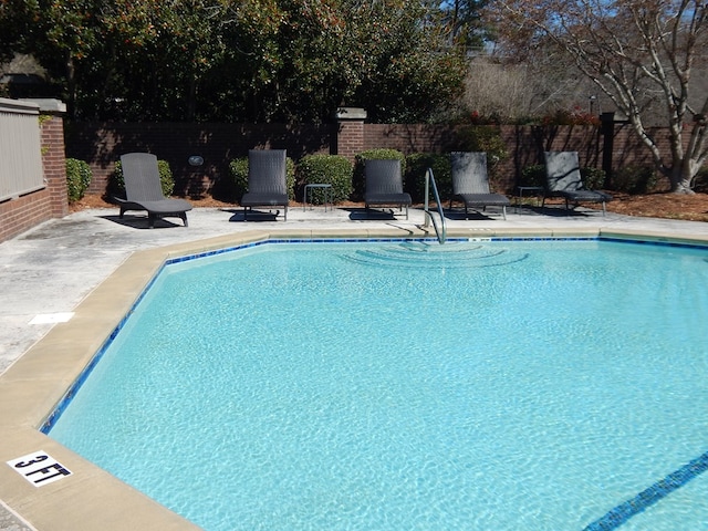 community pool featuring fence and a patio