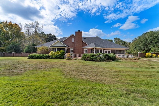 back of property featuring a lawn, a chimney, fence, and a sunroom