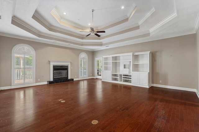 unfurnished living room with hardwood / wood-style floors, a raised ceiling, a high end fireplace, and a ceiling fan