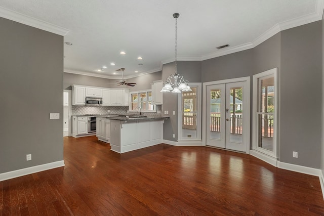 kitchen with white cabinetry, a kitchen breakfast bar, kitchen peninsula, stainless steel appliances, and decorative backsplash