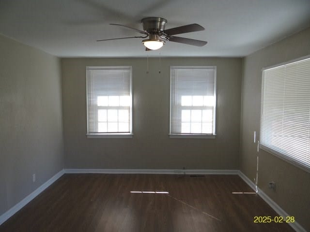 spare room featuring wood finished floors, a wealth of natural light, and baseboards