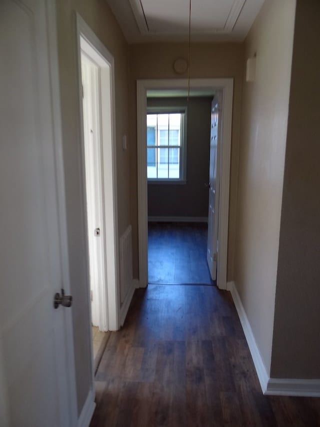 hall with attic access, visible vents, baseboards, and wood finished floors