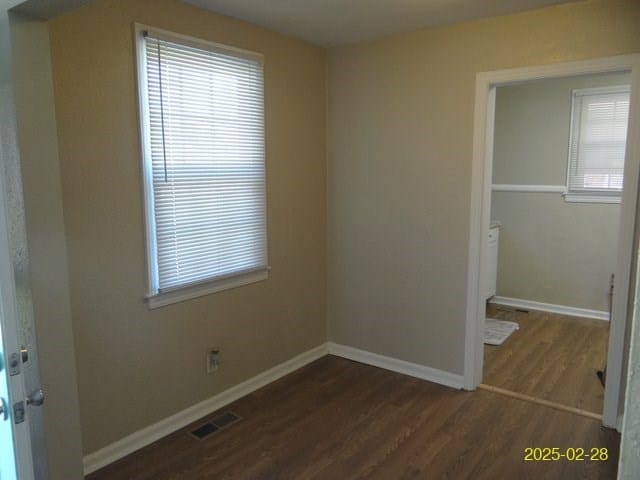 spare room featuring baseboards, visible vents, and dark wood finished floors