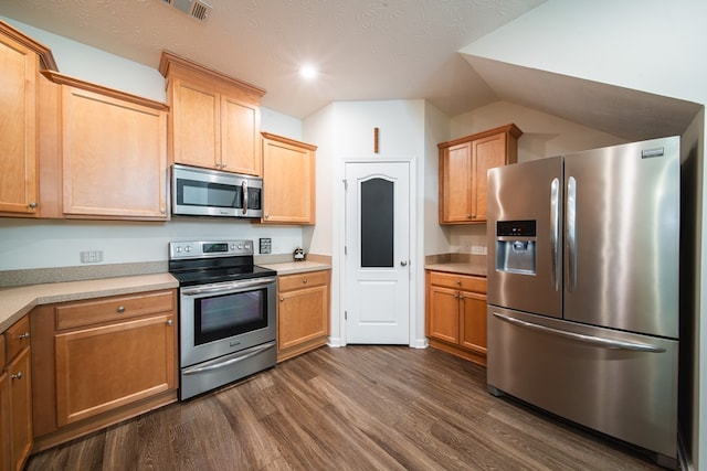 kitchen featuring dark hardwood / wood-style flooring, stainless steel appliances, and vaulted ceiling