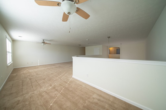 spare room featuring ceiling fan, light colored carpet, and a textured ceiling