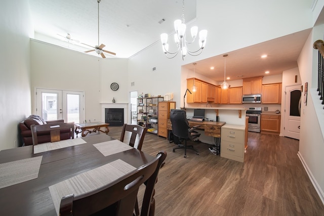 dining area featuring ceiling fan with notable chandelier, dark hardwood / wood-style floors, and a towering ceiling