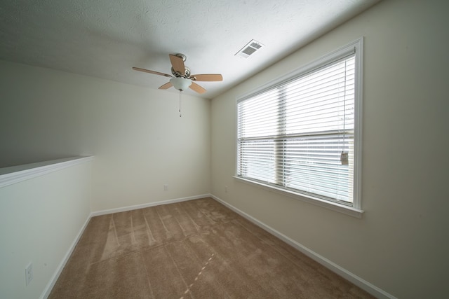 spare room with ceiling fan, light colored carpet, and a textured ceiling