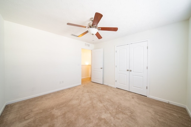 unfurnished bedroom featuring light carpet, ceiling fan, and a closet