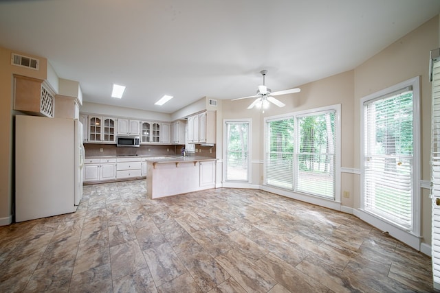 4854 Champions Way, Columbus, GA 31909 - kitchen with freestanding refrigerator, stainless steel microwave, a peninsula, glass insert cabinets, and a ceiling fan