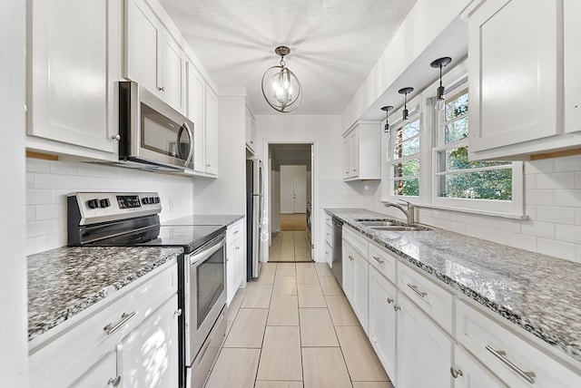 kitchen featuring appliances with stainless steel finishes, white cabinetry, and hanging light fixtures