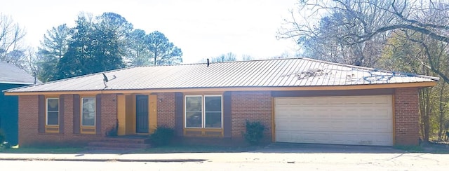 view of front of house featuring a garage, brick siding, and metal roof