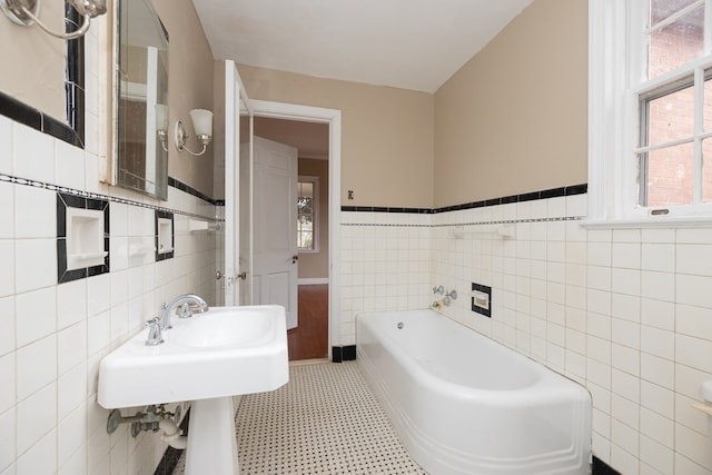 bathroom featuring a garden tub, wainscoting, tile patterned floors, and tile walls