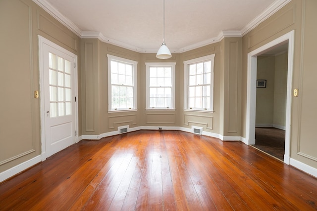 unfurnished dining area featuring crown molding, baseboards, wood-type flooring, and visible vents