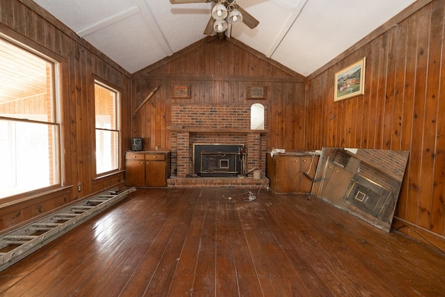 unfurnished living room featuring lofted ceiling with beams, ceiling fan, wooden walls, and hardwood / wood-style flooring