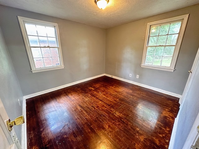 unfurnished room featuring a textured ceiling and dark hardwood / wood-style floors