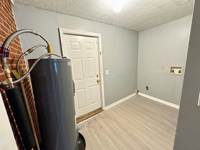 washroom featuring washer hookup, light wood-type flooring, a textured ceiling, and brick wall