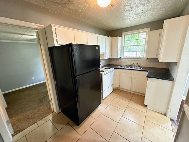 kitchen featuring white cabinets, black fridge, sink, decorative backsplash, and white range oven