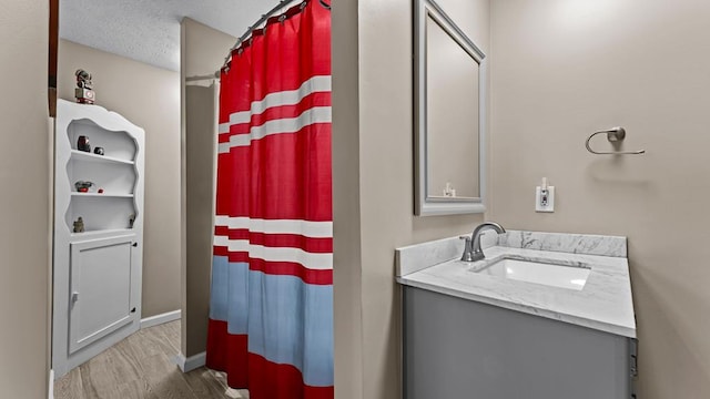 bathroom with hardwood / wood-style flooring, vanity, curtained shower, and a textured ceiling