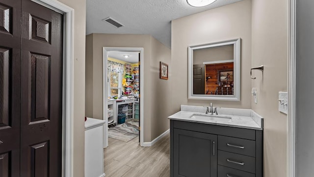 bathroom featuring vanity, wood-type flooring, and a textured ceiling