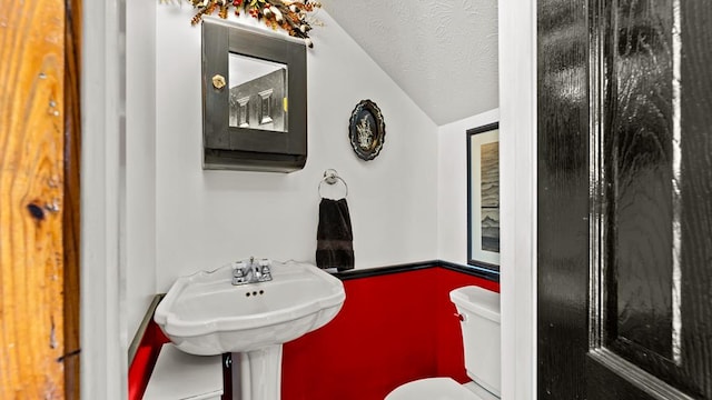 bathroom featuring vaulted ceiling, a textured ceiling, and toilet