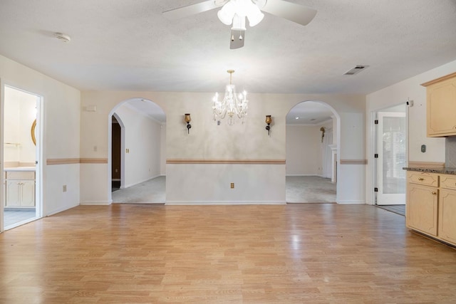 spare room with light wood-type flooring, visible vents, arched walkways, and a textured ceiling