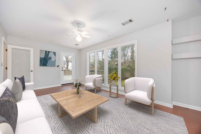 living area featuring visible vents, ceiling fan, and baseboards