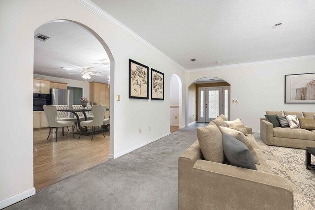 living area featuring ornamental molding, arched walkways, visible vents, and baseboards