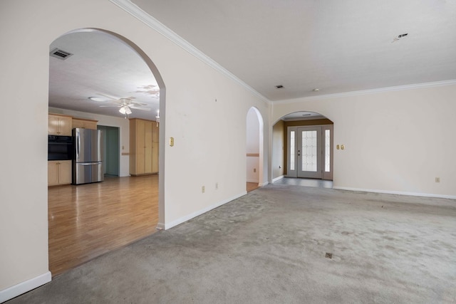 empty room featuring light colored carpet, arched walkways, visible vents, and crown molding