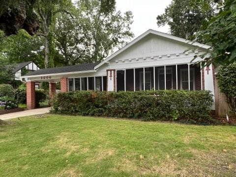 rear view of property with a lawn and a sunroom