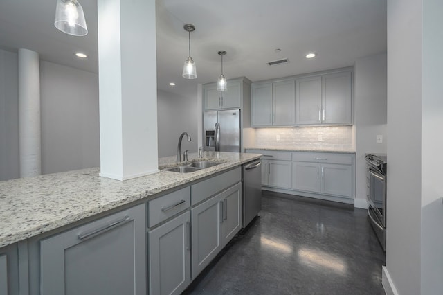 kitchen with gray cabinets, a sink, tasteful backsplash, appliances with stainless steel finishes, and light stone countertops