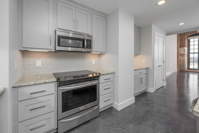 kitchen with baseboards, light stone countertops, decorative backsplash, recessed lighting, and stainless steel appliances