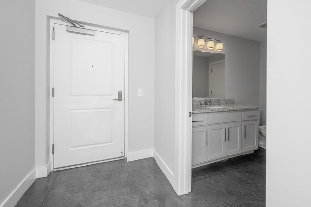 interior space featuring baseboards, toilet, finished concrete flooring, and vanity