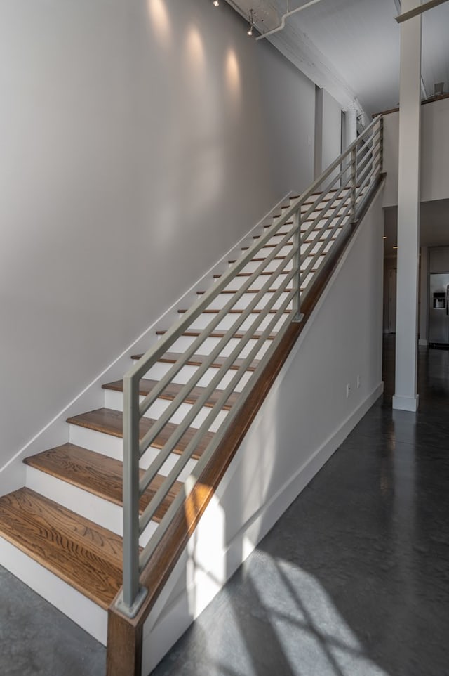 stairway featuring finished concrete flooring and baseboards