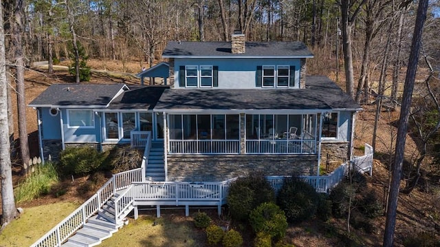 view of front of house featuring a sunroom, stone siding, stairway, stucco siding, and a chimney