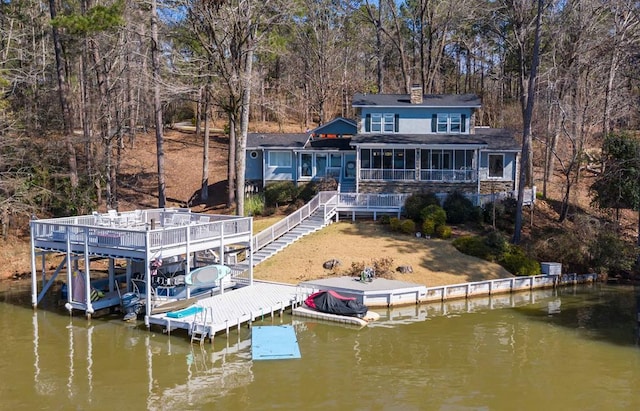 dock area featuring stairway, a deck with water view, and boat lift