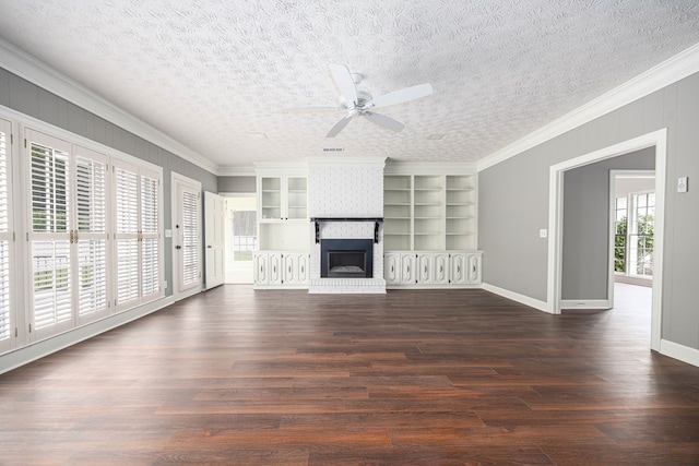 unfurnished living room with dark wood finished floors, crown molding, built in shelves, and ceiling fan