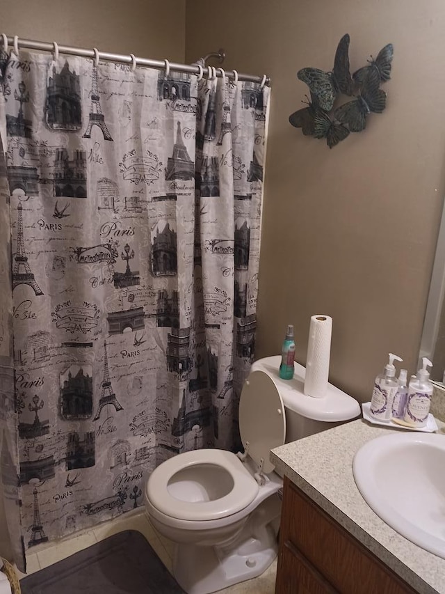 bathroom featuring tile patterned flooring, vanity, a shower with shower curtain, and toilet