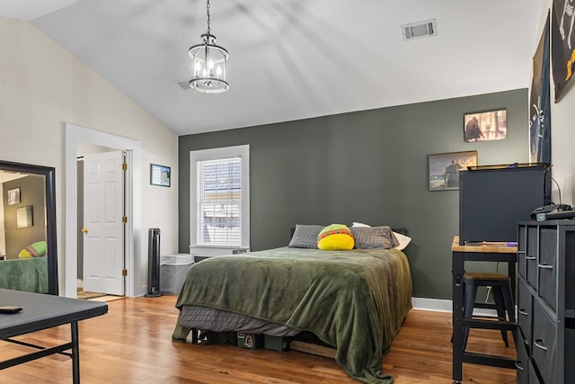bedroom featuring wood finished floors, baseboards, vaulted ceiling, and visible vents