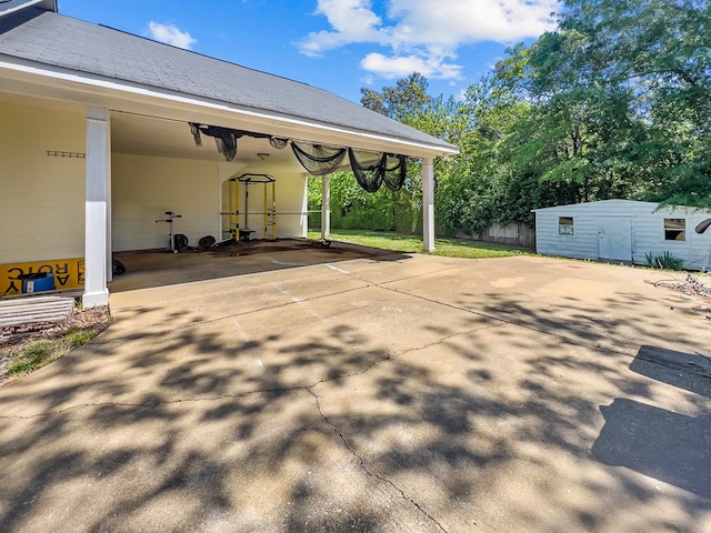 view of patio / terrace featuring an outbuilding, an attached carport, a storage unit, and concrete driveway