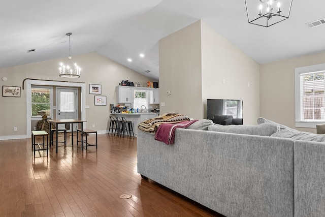 living room featuring lofted ceiling, dark wood-style floors, visible vents, and a notable chandelier