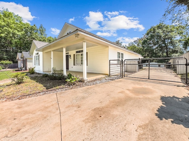 view of front of house with a gate, covered porch, concrete driveway, and fence