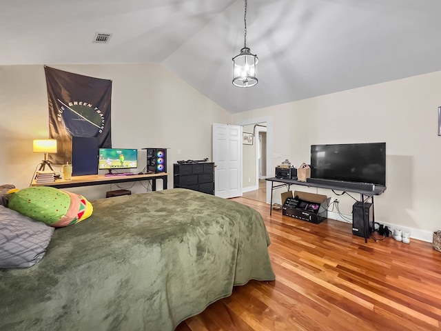 bedroom with vaulted ceiling, wood finished floors, visible vents, and baseboards